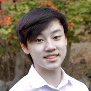 An outdoor headshot of student Jay Kim who has short, dark hair, parted to the side. Kim is smiling and wearing a light colored polo shirt.